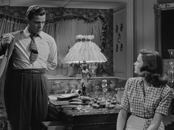 Movie still from “Laura” (1944), directed by Rouben Mamoulian – A man and a woman are standing in front of a lamp; Medium shot, Low angle