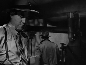 Movie still from “Laura” (1944), directed by Rouben Mamoulian – A black and white photo of a man wearing a hat; Medium shot, Low angle