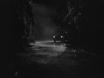 Movie still from “Laura” (1944), directed by Rouben Mamoulian – A car driving down a road in the rain; Extreme Wide shot, High angle