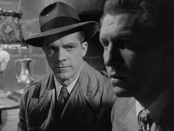 Movie still from “Laura” (1944), directed by Rouben Mamoulian – A man in a hat and a man in a suit; Close Up shot, Low angle