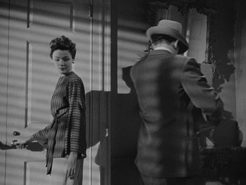 Movie still from “Laura” (1944), directed by Rouben Mamoulian – A man and a woman standing next to each other in front of a mirror; Medium shot, Low angle