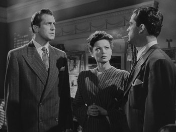 Movie still from “Laura” (1944), directed by Rouben Mamoulian – Two men and a woman standing in front of each other in a room; Medium shot, Low angle