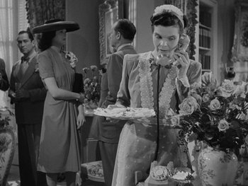 Movie still from “Laura” (1944), directed by Rouben Mamoulian – A woman holding a tray talking on the phone; Medium shot, High angle
