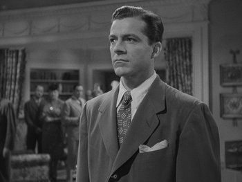 Movie still from “Laura” (1944), directed by Rouben Mamoulian – A black and white photo of a man in a suit and tie; Medium shot, Low angle