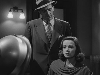 Movie still from “Laura” (1944), directed by Rouben Mamoulian – A man and a woman are standing in front of a mirror; Medium shot, Over the shoulder angle