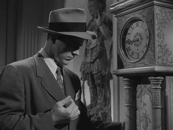 Movie still from “Laura” (1944), directed by Rouben Mamoulian – A black and white photo of a man in a suit and hat looking at a clock; Medium shot, Low angle