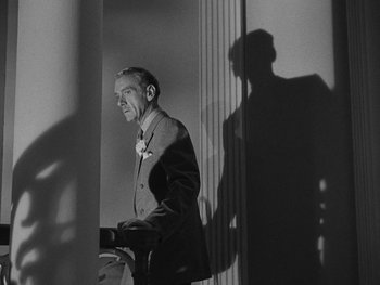 Movie still from “Laura” (1944), directed by Rouben Mamoulian – A black and white photo of a man in a suit and bow tie; Medium shot, Low angle