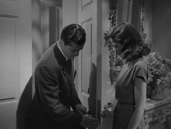 Movie still from “Laura” (1944), directed by Rouben Mamoulian – A man and a woman standing next to each other in front of a door; Medium shot, High angle