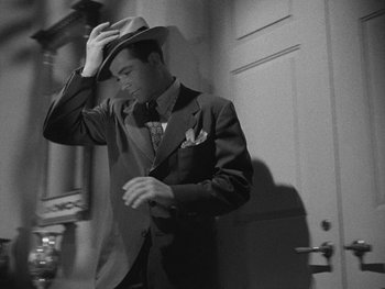 Movie still from “Laura” (1944), directed by Rouben Mamoulian – A black and white photo of a man wearing a suit and hat; Medium shot, Low angle