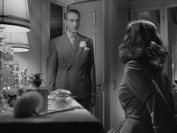 Movie still from “Laura” (1944), directed by Rouben Mamoulian – A black and white photo of a man in a suit looking into a mirror; Medium shot, Over the shoulder angle