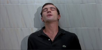 Movie still from “Law of Desire” (1987), directed by Pedro Almodóvar – A man with his eyes closed in a black shirt; Close Up shot, Overhead angle