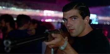 Movie still from “Law of Desire” (1987), directed by Pedro Almodóvar – A man holding a gun in his hands; Close Up shot, Low angle