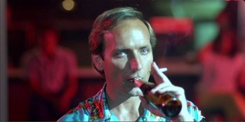 Movie still from “Law of Desire” (1987), directed by Pedro Almodóvar – A man holding a bottle of beer and smoking a cigarette; Close Up shot, Low angle