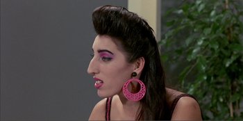 Movie still from “Law of Desire” (1987), directed by Pedro Almodóvar – A woman with pink lipstick and pink eye shadow; Close Up shot, Over the shoulder angle