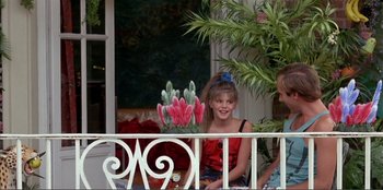 Movie still from “Law of Desire” (1987), directed by Pedro Almodóvar – A young girl sitting on a porch next to a plant; Medium shot, High angle