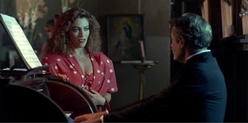 Movie still from “Law of Desire” (1987), directed by Pedro Almodóvar – A woman in a polka dot dress talking to a man in a black suit; Medium shot, Over the shoulder angle