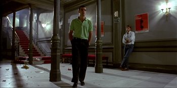 Movie still from “Law of Desire” (1987), directed by Pedro Almodóvar – A man in a green shirt is standing next to a man in black pants; Wide shot, Low angle