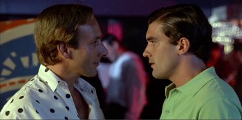 Movie still from “Law of Desire” (1987), directed by Pedro Almodóvar – A couple of men standing next to each other; Close Up shot, Over the shoulder angle