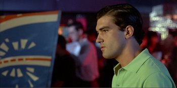 Movie still from “Law of Desire” (1987), directed by Pedro Almodóvar – A man in a green shirt is looking at something in the distance; Close Up shot, Low angle