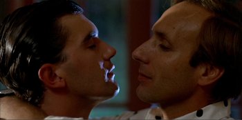 Movie still from “Law of Desire” (1987), directed by Pedro Almodóvar – A couple of men standing next to each other; Close Up shot, Low angle