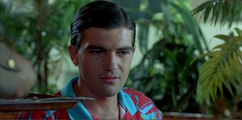 Movie still from “Law of Desire” (1987), directed by Pedro Almodóvar – A person wearing a hawaiian shirt; Close Up shot, Over the shoulder angle