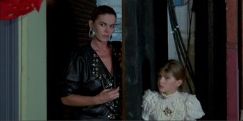 Movie still from “Law of Desire” (1987), directed by Pedro Almodóvar – A woman and a girl are standing next to each other; Medium shot, Low angle