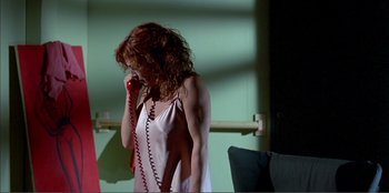 Movie still from “Law of Desire” (1987), directed by Pedro Almodóvar – A woman is talking on a phone while standing in a room; Medium shot, Low angle