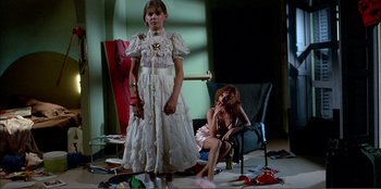 Movie still from “Law of Desire” (1987), directed by Pedro Almodóvar – Two young girls sitting on the floor in front of a chair; Wide shot, Low angle