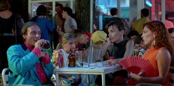 Movie still from “Law of Desire” (1987), directed by Pedro Almodóvar – A woman sitting at a table in front of a child; Medium shot, Over the shoulder angle