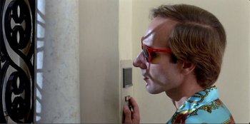 Movie still from “Law of Desire” (1987), directed by Pedro Almodóvar – A man with red glasses is looking into a mirror; Close Up shot, Low angle