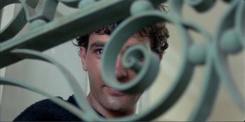 Movie still from “Law of Desire” (1987), directed by Pedro Almodóvar – A man's face through a metal fence; Close Up shot, Low angle
