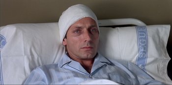 Movie still from “Law of Desire” (1987), directed by Pedro Almodóvar – A man with a bandage on his head laying in a bed; Close Up shot, High angle