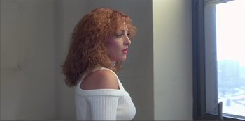 Movie still from “Law of Desire” (1987), directed by Pedro Almodóvar – A woman with red hair wearing a white sweater; Close Up shot, Low angle