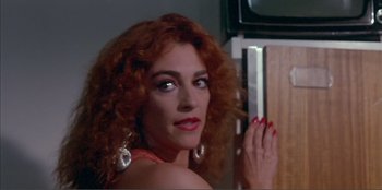 Movie still from “Law of Desire” (1987), directed by Pedro Almodóvar – A woman with red curly hair is posing for a picture; Close Up shot, Low angle
