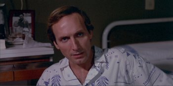 Movie still from “Law of Desire” (1987), directed by Pedro Almodóvar – A person wearing a white and blue shirt; Close Up shot, Over the shoulder angle