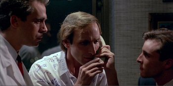 Movie still from “Law of Desire” (1987), directed by Pedro Almodóvar – A man talking on a cell phone while another man looks on; Close Up shot, Low angle