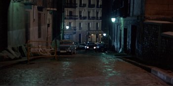 Movie still from “Law of Desire” (1987), directed by Pedro Almodóvar – Cars parked on the side of the street at night; Extreme Wide shot, High angle