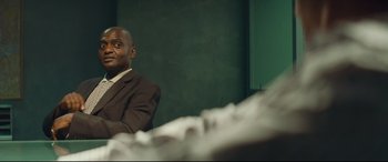 Movie still from “Layer Cake” (2004), directed by Matthew Vaughn – A man in a suit sitting in front of a mirror; Medium shot, Low angle