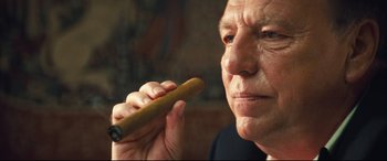 Movie still from “Layer Cake” (2004), directed by Matthew Vaughn – An older man holding a cigar in his hand; Close Up shot, Low angle
