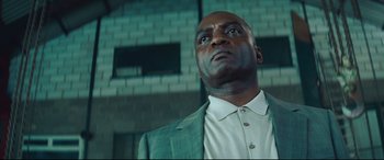 Movie still from “Layer Cake” (2004), directed by Matthew Vaughn – A man in a green suit looking up at the sky; Close Up shot, Low angle