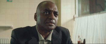 Movie still from “Layer Cake” (2004), directed by Matthew Vaughn – A person wearing a suit and tie; Close Up shot, Low angle