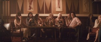 Movie still from “Layer Cake” (2004), directed by Matthew Vaughn – A group of people sitting around a table drinking and smoking; Wide shot, Low angle