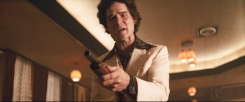 Movie still from “Layer Cake” (2004), directed by Matthew Vaughn – A man in a white jacket holding a gun in his hand; Close Up shot, Low angle