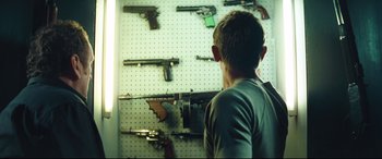 Movie still from “Layer Cake” (2004), directed by Matthew Vaughn – A young boy looking at a wall of guns; Medium shot, Low angle