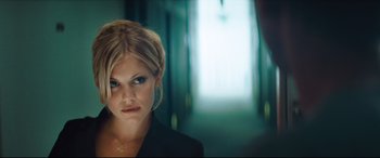 Movie still from “Layer Cake” (2004), directed by Matthew Vaughn – A woman in a black jacket is looking at the camera; Close Up shot, Over the shoulder angle