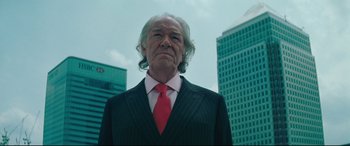 Movie still from “Layer Cake” (2004), directed by Matthew Vaughn – An older man wearing a suit and red neck tie; Close Up shot, Low angle