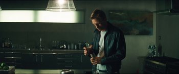 Movie still from “Layer Cake” (2004), directed by Matthew Vaughn – A man in a leather jacket is holding a bottle of alcohol; Medium shot, Low angle
