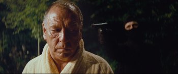 Movie still from “Layer Cake” (2004), directed by Matthew Vaughn – An older man in a robe looking down at the camera; Close Up shot, Over the shoulder angle