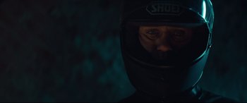Movie still from “Layer Cake” (2004), directed by Matthew Vaughn – A person wearing a motorcycle helmet in the dark; Close Up shot, Overhead angle