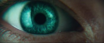Movie still from “Layer Cake” (2004), directed by Matthew Vaughn – A person's eye with green lighting; Extreme Close Up shot, Overhead angle